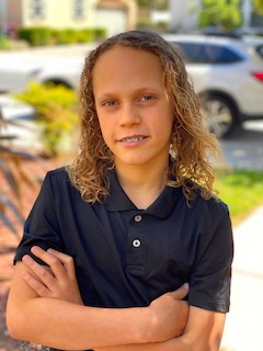 A headshot of Jace smiling at camera with arms crossed